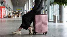 Woman sitting on her luggage in airport terminal, waiting for a delayed flight