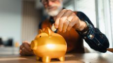 Senior man putting coins into a piggy bank