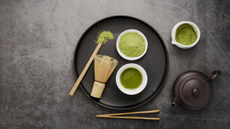 Matcha powder and black teapot on grey slate background